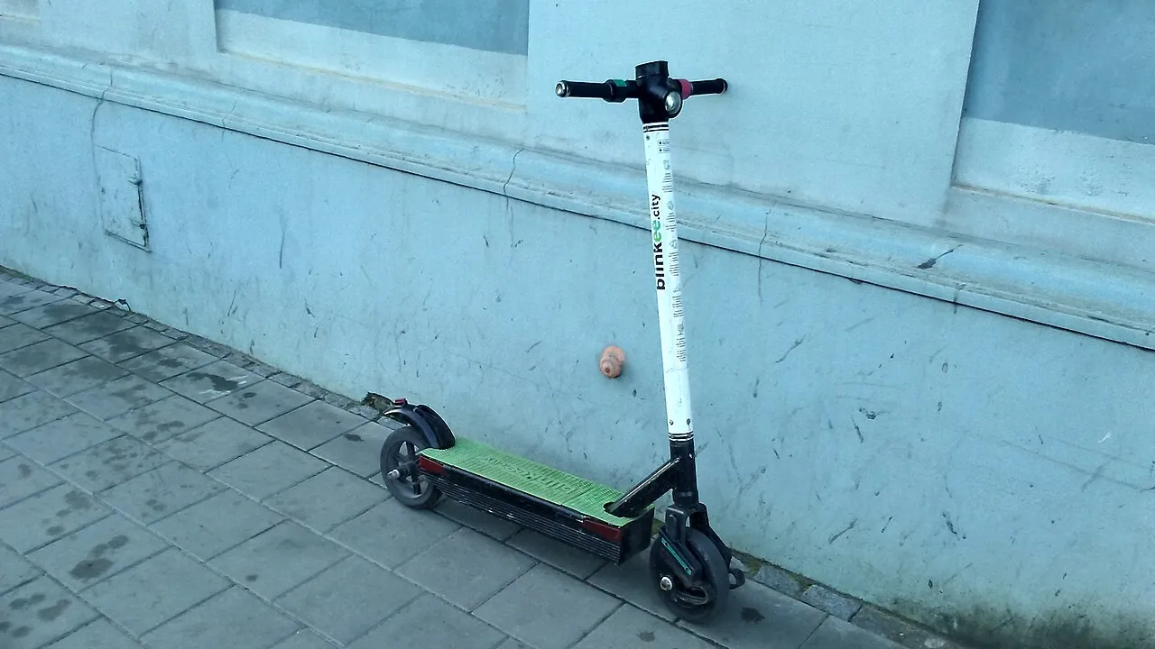 Een deel-e-scooter staat geparkeerd tegen een muur op een stoep.